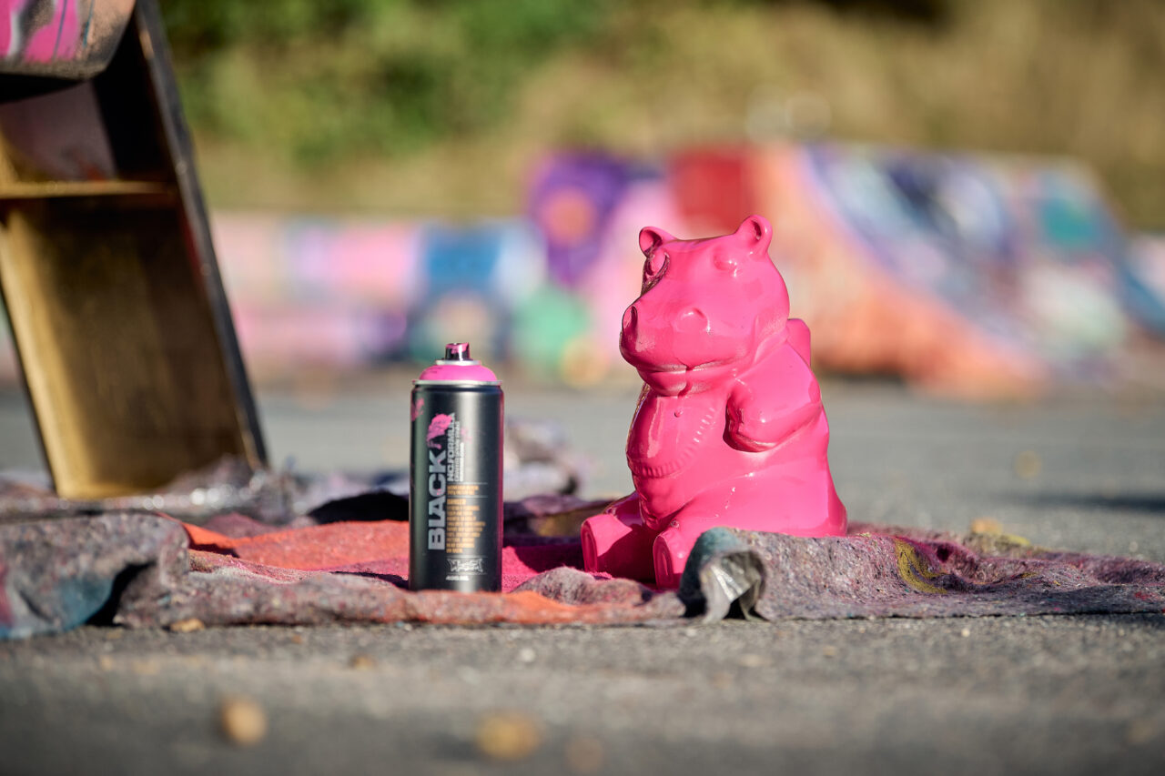 Eine mit pinker Sprühfarbe angesprühte Nilpferd-Figur, die Sprühflasche daneben